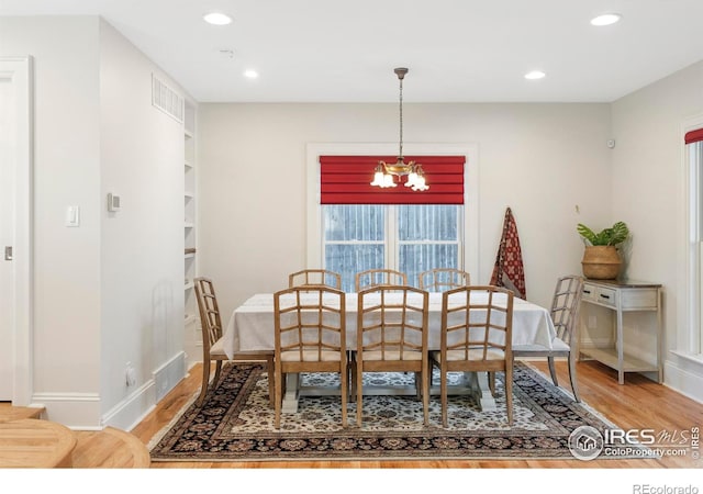 dining space featuring a chandelier, hardwood / wood-style floors, and built in shelves