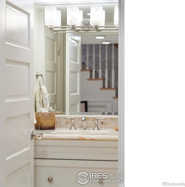 bathroom featuring vanity, backsplash, and a chandelier