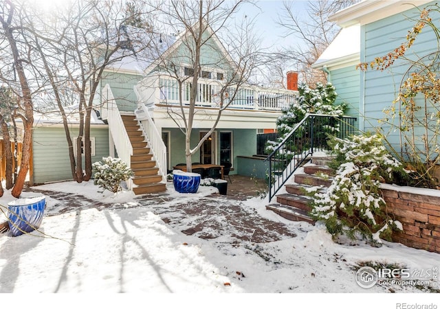 snow covered rear of property featuring a balcony