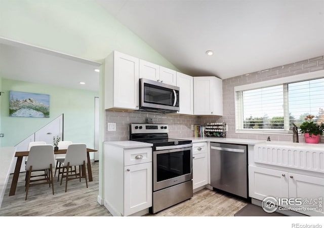 kitchen with white cabinetry, light wood-type flooring, lofted ceiling, and appliances with stainless steel finishes