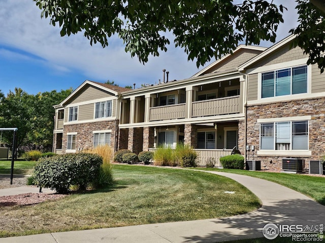 view of front of house featuring a front lawn, a balcony, and central AC unit