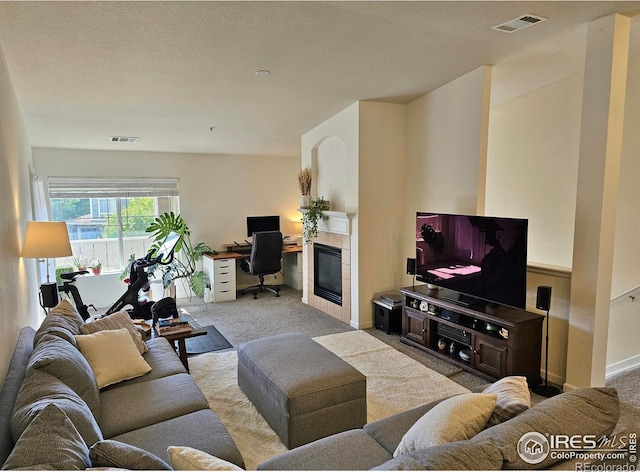 carpeted living room featuring a tiled fireplace