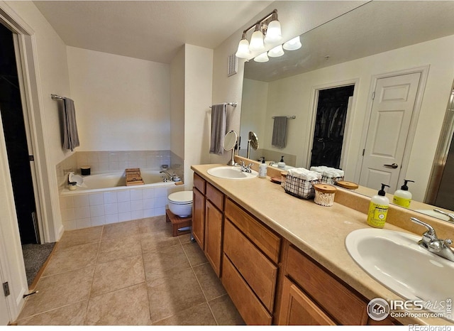 bathroom with tile patterned floors, vanity, and a relaxing tiled tub