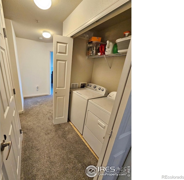 clothes washing area featuring washer and dryer, a textured ceiling, and dark carpet