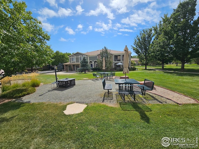 view of property's community featuring a lawn and a patio area