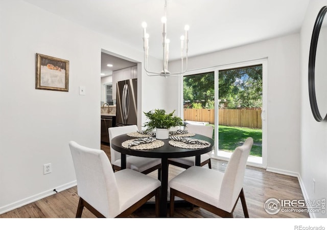 dining space featuring a chandelier, light wood-type flooring, and baseboards