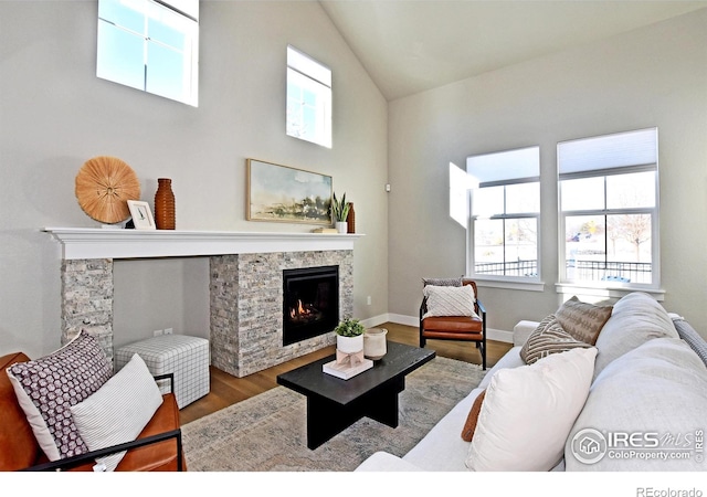 living room featuring a stone fireplace, lofted ceiling, and hardwood / wood-style flooring