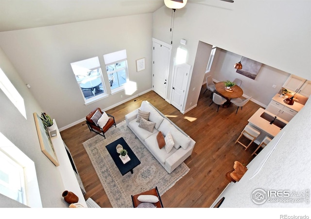 living room featuring ceiling fan, high vaulted ceiling, and dark wood-type flooring