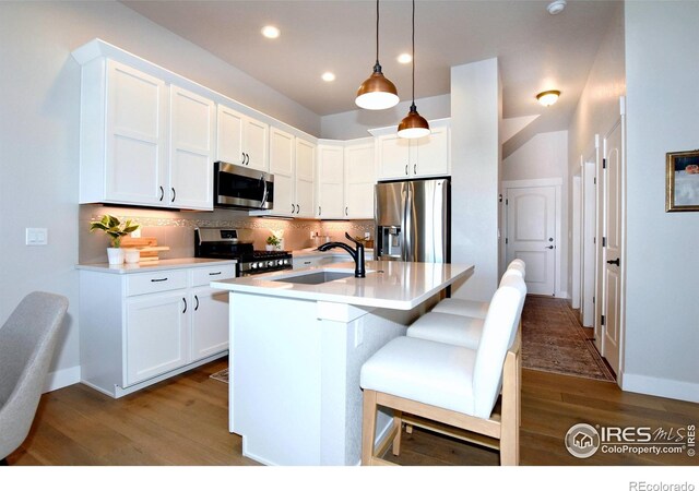 kitchen featuring white cabinets, appliances with stainless steel finishes, a center island with sink, and sink