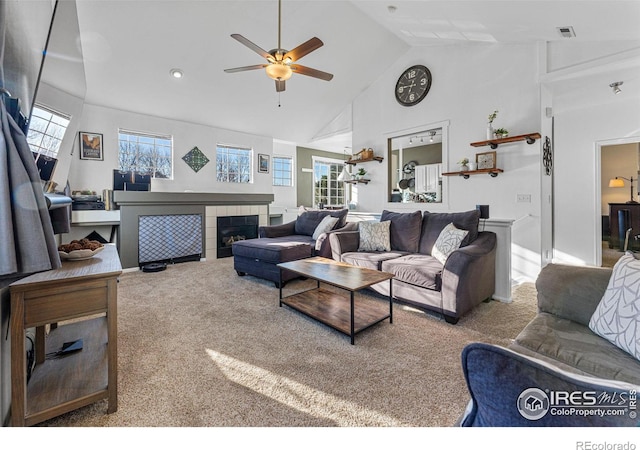 living room featuring ceiling fan, a fireplace, high vaulted ceiling, and light colored carpet