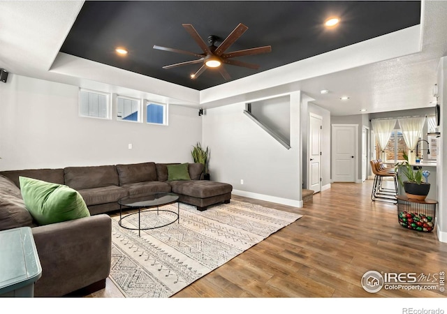 living room featuring a raised ceiling, ceiling fan, and hardwood / wood-style floors