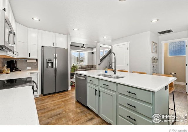 kitchen featuring ceiling fan, sink, stainless steel appliances, a kitchen island with sink, and green cabinetry