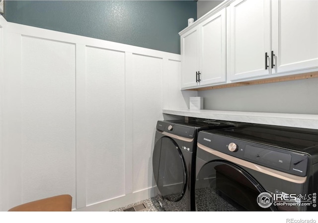 clothes washing area with washer and dryer and cabinets