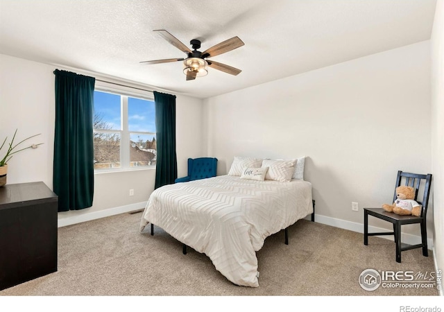 carpeted bedroom featuring ceiling fan and a textured ceiling