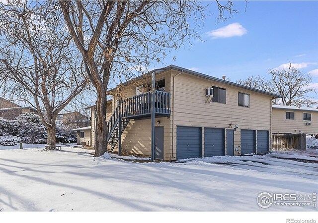 snow covered property with stairway and a garage