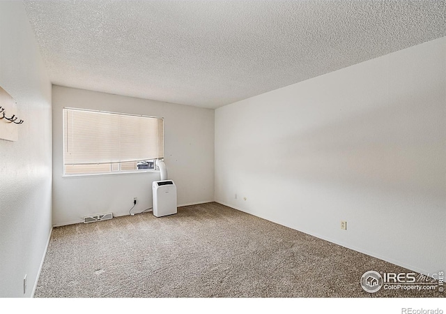 spare room with visible vents, carpet, and a textured ceiling