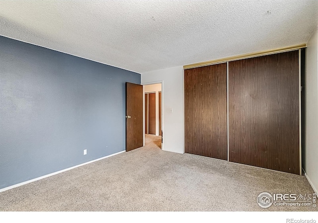 unfurnished bedroom with a closet, a textured ceiling, and carpet floors