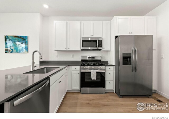 kitchen with white cabinetry, sink, appliances with stainless steel finishes, and light hardwood / wood-style flooring