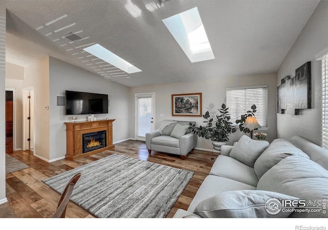 living room with a textured ceiling, a healthy amount of sunlight, lofted ceiling, and wood-type flooring