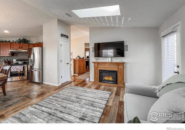 living room with dark hardwood / wood-style flooring, a textured ceiling, and vaulted ceiling