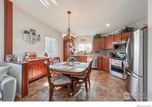 dining space featuring a textured ceiling, a notable chandelier, lofted ceiling, and sink