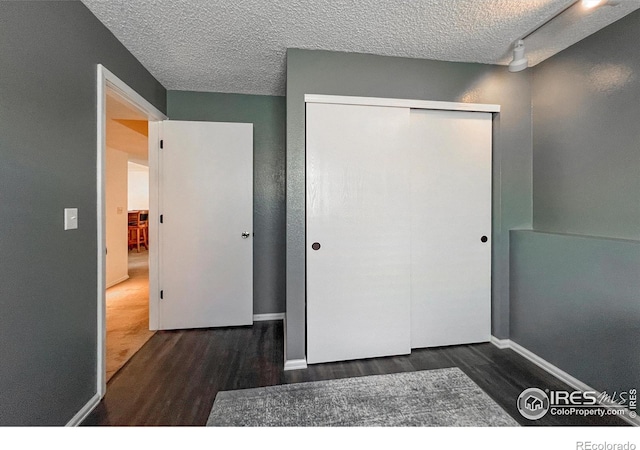 bedroom featuring a closet, dark hardwood / wood-style flooring, and a textured ceiling