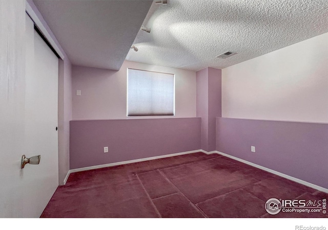 carpeted spare room featuring a textured ceiling