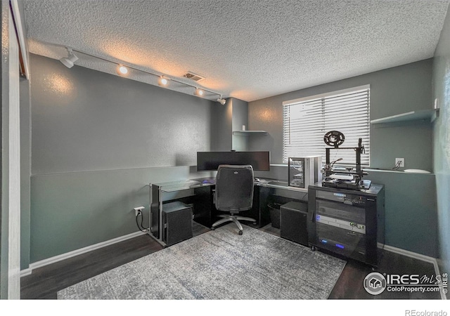 office with a textured ceiling, dark hardwood / wood-style flooring, and rail lighting