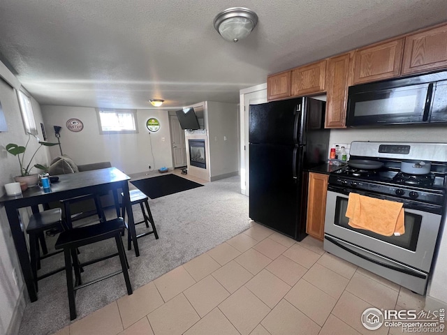 kitchen featuring light carpet, a textured ceiling, and black appliances