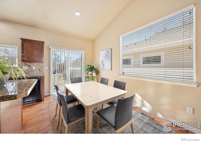 dining room with light wood-type flooring and vaulted ceiling