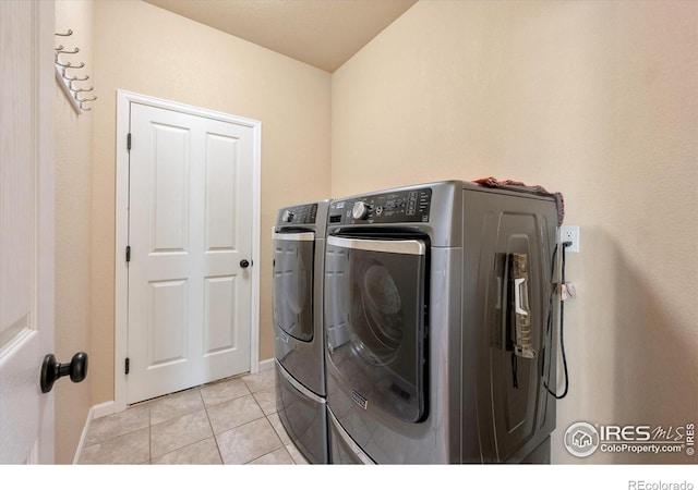 clothes washing area with independent washer and dryer and light tile patterned flooring