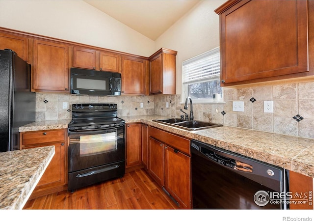 kitchen with dark hardwood / wood-style floors, black appliances, tasteful backsplash, lofted ceiling, and sink