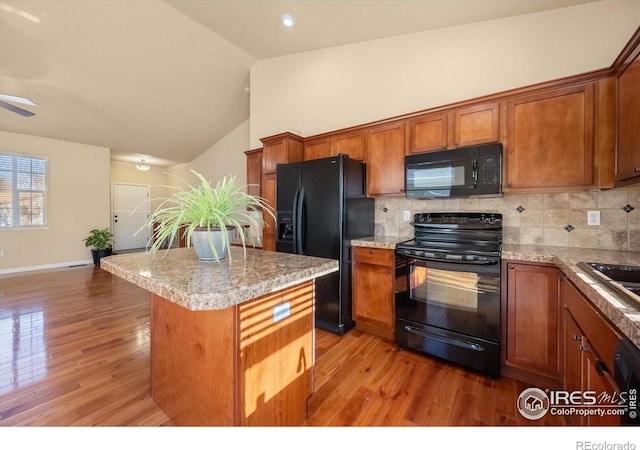 kitchen with light hardwood / wood-style flooring, black appliances, tasteful backsplash, and a center island