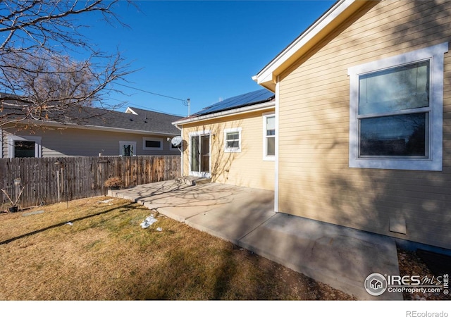 back of property featuring a lawn, a patio, and solar panels