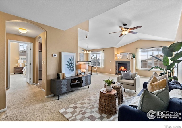 living room featuring light carpet, a tile fireplace, lofted ceiling, and ceiling fan