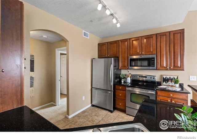 kitchen featuring light tile patterned floors, a textured ceiling, and appliances with stainless steel finishes