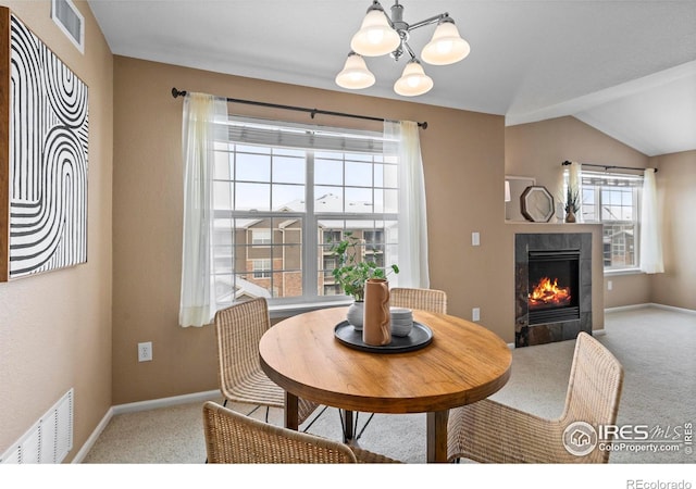 dining area with a tile fireplace, carpet flooring, a chandelier, and lofted ceiling