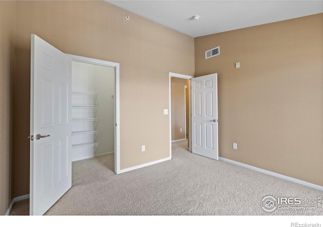 unfurnished bedroom with light colored carpet, a spacious closet, and a closet