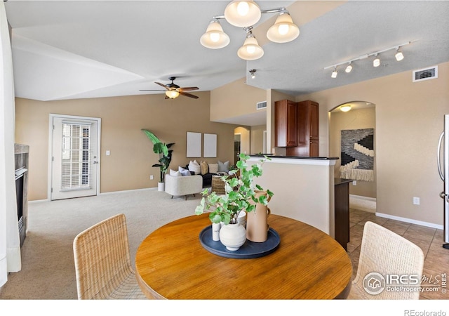 dining space featuring ceiling fan with notable chandelier, lofted ceiling, and light carpet