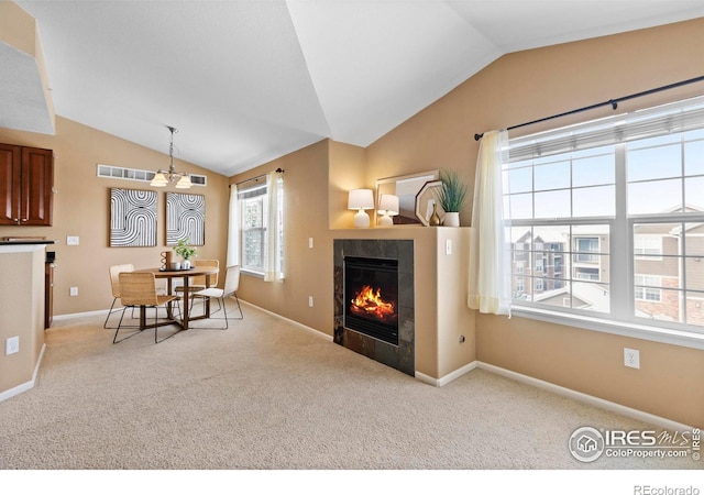 dining space with a healthy amount of sunlight, light colored carpet, and a tiled fireplace