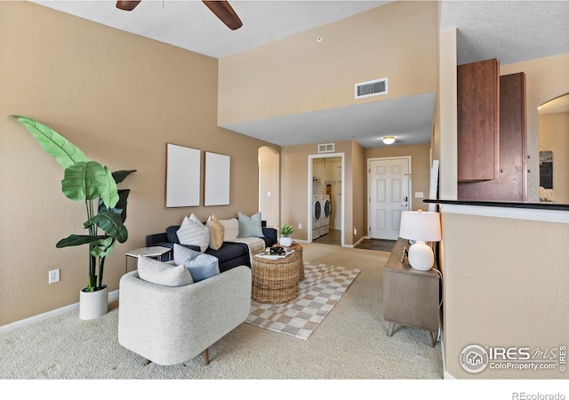 living room with washing machine and dryer, ceiling fan, and light colored carpet