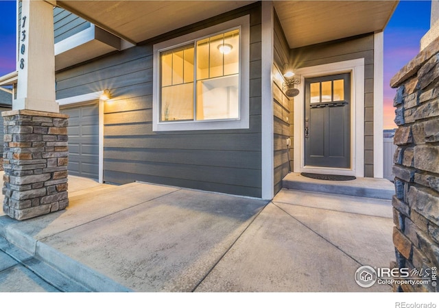 exterior entry at dusk featuring a garage