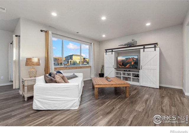 living room featuring a barn door and dark hardwood / wood-style floors