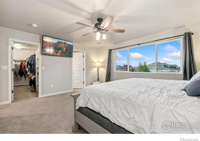 bedroom featuring a closet, a spacious closet, ceiling fan, and light colored carpet