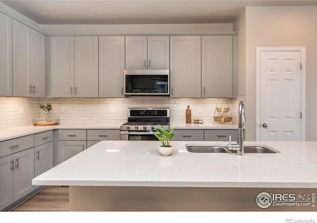 kitchen featuring decorative backsplash, gray cabinets, sink, and stainless steel appliances