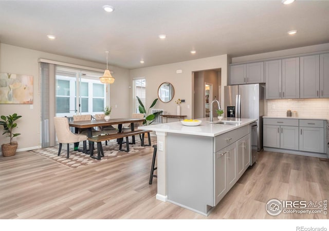 kitchen featuring gray cabinetry, sink, an island with sink, and light hardwood / wood-style flooring