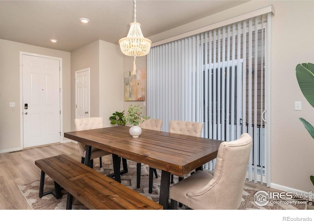 dining area with light hardwood / wood-style floors and a notable chandelier