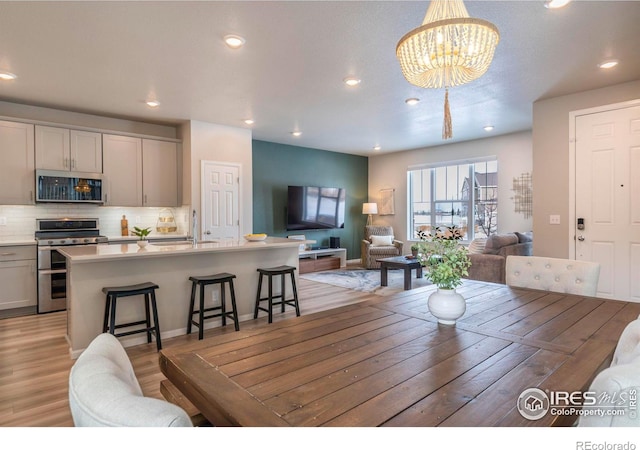 dining space with sink, a chandelier, and light hardwood / wood-style flooring