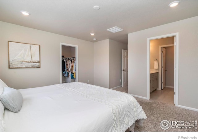 carpeted bedroom with ensuite bathroom, a walk in closet, and a closet