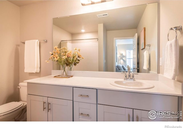 bathroom featuring vanity, toilet, and walk in shower